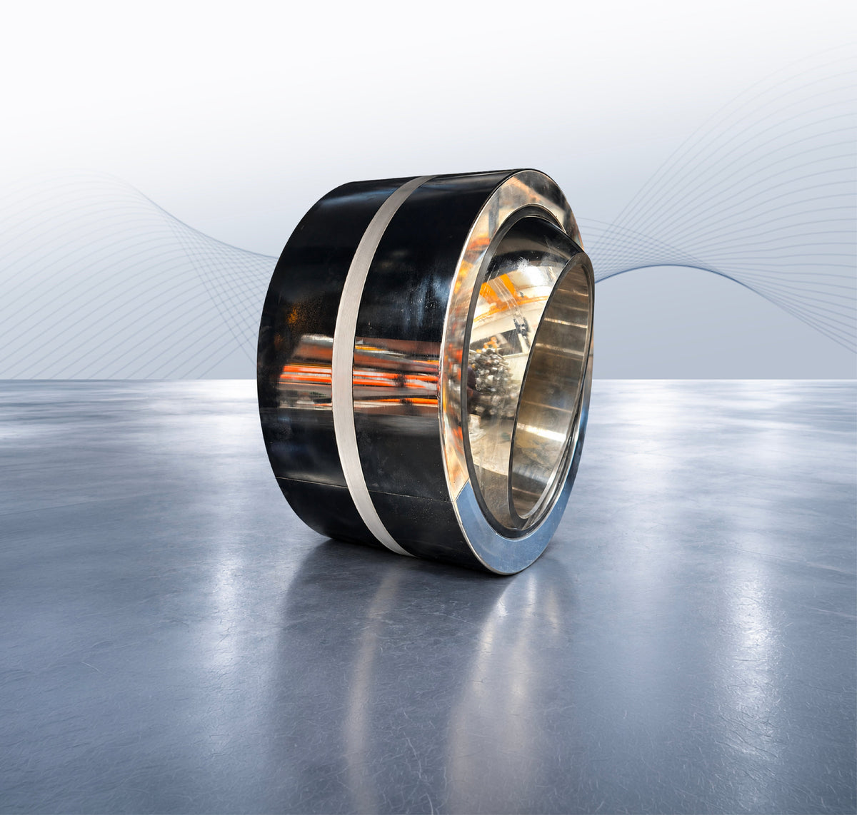 Heavy equipment bearing with a polished inner ring and dark outer surface on a grey display floor.