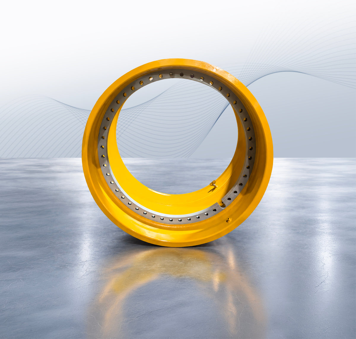 Yellow heavy equipment wheel rim with a machined mounting ring and bolt holes.